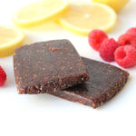 Chocolate energy bars with raspberries and lemon slices on white background.